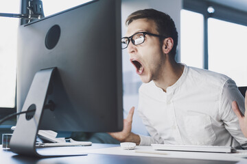 Angry office worker shouting at the computer