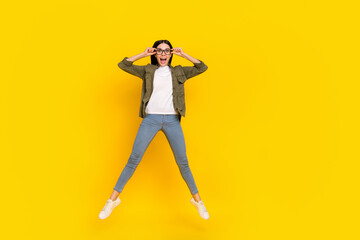 Fototapeta na wymiar Full length photo of impressed young lady jump wear eyewear shirt jeans shoes isolated on yellow background