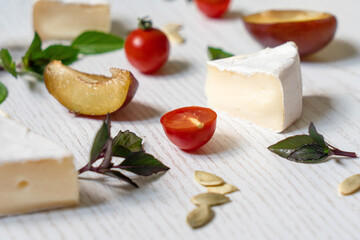 Charcuterie board of assorted cheeses, vegetables and appetizers. Above Top view table scene on a white wood background.