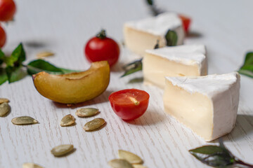 Charcuterie board of assorted cheeses, vegetables and appetizers. Above Top view table scene on a white wood background.