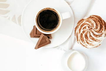 Dark chocolate and cocoa chocolate cupcakes with a cup of hot black coffee on green napkin. Space for text