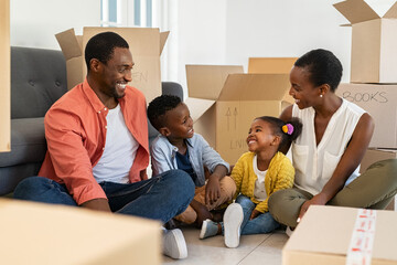 Black family sitting with cardboard boxes during moving house
