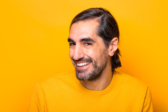 Cheerful man looking at camera in yellow studio