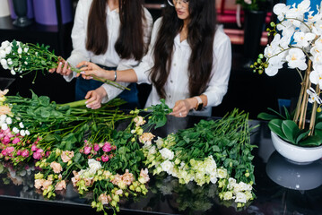 Close-up of women's hands collecting and making beautiful festive bouquets in a cozy flower shop. Floristry and bouquet making in a flower shop. Small business.