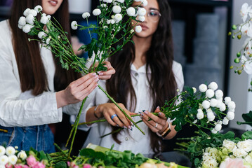 Close-up of women's hands collecting and making beautiful festive bouquets in a cozy flower shop. Floristry and bouquet making in a flower shop. Small business.
