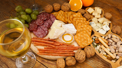 Snack for wine. Cheese and meat plate. Sausage, cheese, nuts, grapes, crackers on wooden table. Italian food for romantic date or meeting with friends