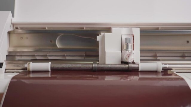 The cutting plotter cuts out a pattern on brown vinyl film
