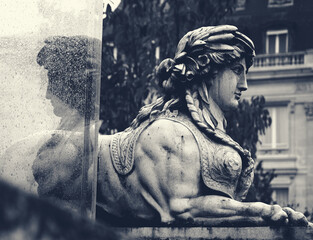 Parisian autumnal mystery. Sphinx and its reflection in wet glass after rain. Moody dark monochrome photo