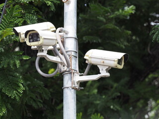 Four surveillance cameras are mounted on steel poles along the sidewalks to record and monitor the...