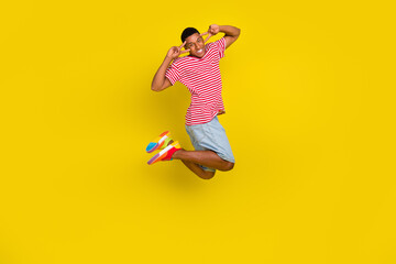 Fototapeta na wymiar Full body photo of guy jump make v-sign eye wear red striped t-shirt short isolated over bright yellow color background
