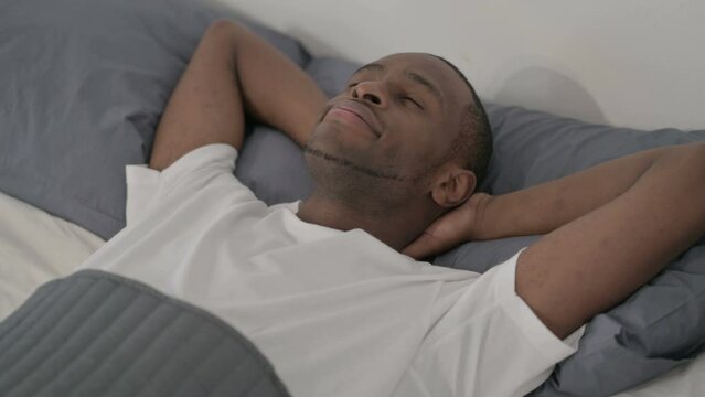 African Man Laying in Bed Awake Thinking 