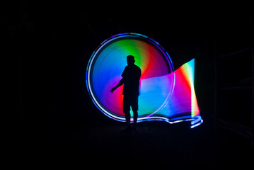 One person standing alone against beautiful color circle LED light painting as the backdrop	