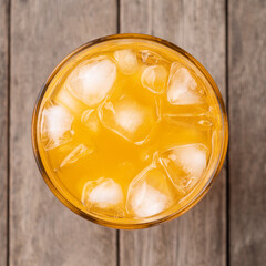 Orange soda, soft drink in a cup with ice, top view over wooden table