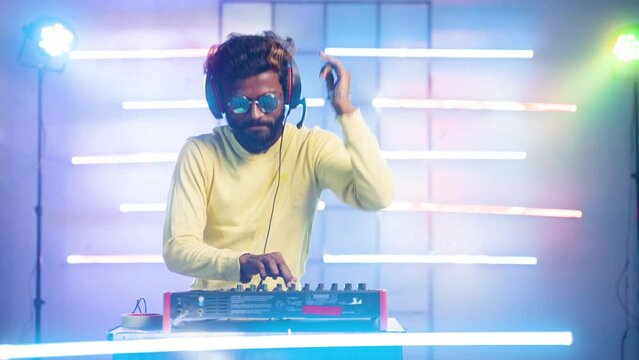 exicted dj sound device oprator with headphones y dancing at club - concept of entertainment, nightlife, music club and musician