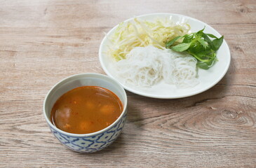 rice noodles dressing with meat ball fish curry sauce and fresh vegetable on plate