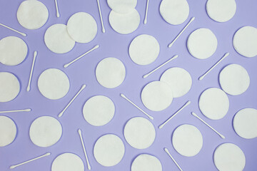 Hygiene cotton pads and cotton sticks on textured purple background. Top view, copy space, pattern