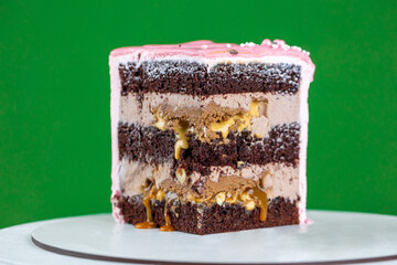 Pink cream cheese cake Slice with chocolate chip gouges decorated with meringues and isomalt lollipops. Beautiful delicious birthday cake on the green background. Picture for a menu