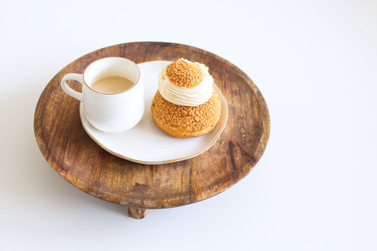 Tasty coffee and craquelin choux pastry cream-puff dessert filled with cream on a wooden plate.
