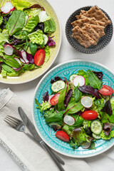 Two bowls of salad with bread on white background. Tasty and healthy food concept. Flat lay..