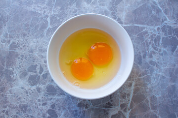 Top view raw egg yolk in bowl on marble background.
