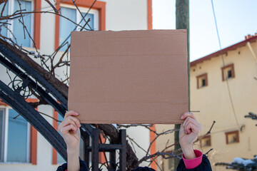 Protester's hand holding blank cardboard box with copy space.
