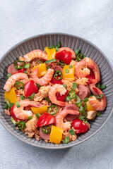 Jambalaya rice with chicken, shrimp, sausage and vegetables in plate on gray concrete table