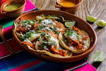 Mexican tacos al pastor accompanied by vegetables and sauces