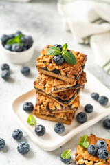 Shortbread bar cookies with blueberries on a serving plate on a light gray kitchen table. Delicious homemade sweet pastries