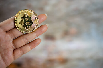 Close up one golden coin with the bitcoin symbol in hand. Young hand holding cryptocurrency coin.