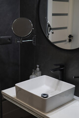 Photo of a modern loft black interior of a bathroom. Big washbasin with mirrors