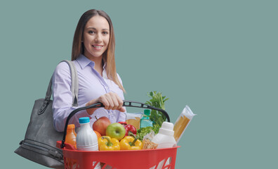 Obraz na płótnie Canvas Young woman holding a full shopping basket
