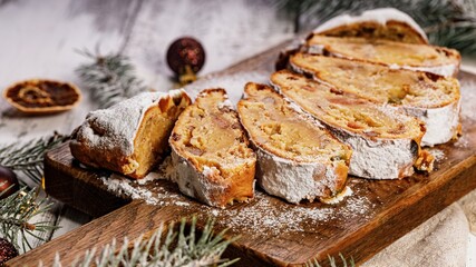Food banner. Christmas stollen on a cutting board. Wooden white table background. Traditional Christmas pastry with marzipan, nuts, raisins and dried fruit.