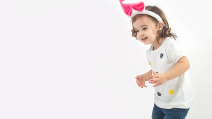 Easter egg hunt concept. Little girl with rabbit ears sneaks on a white background. Copy space. Studio