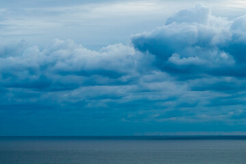 Obraz premium Panoramic view of bright blue sea, blue sky with fluffy white clouds