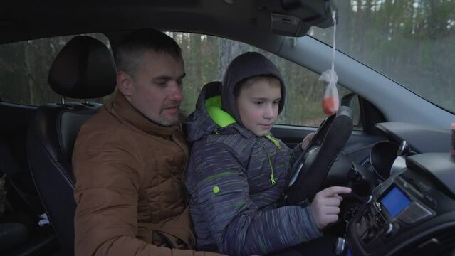 Father showing and teaching his young son car dashboard. Parents and offspring relationship.