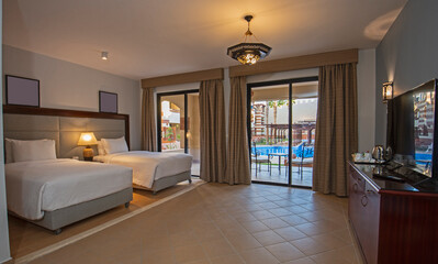 Twin beds in suite of a luxury hotel room with terrace and pool view