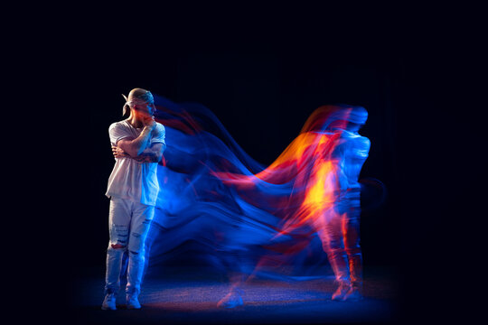 Split personality. Sportive man in sports white uniform and do-rag dancing hip-hop isolated on dark background in mixed neon light. Youth culture, style and fashion