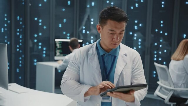 Portrait asian chinese IT developer wearing white laboratory science coat using tablet computer monitoring server racks in modern datacenter. Database. Cloud computing.