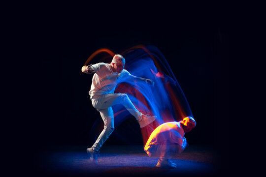 Split personality. Sportive man in sports white uniform and do-rag dancing hip-hop isolated on dark background in mixed neon light. Youth culture, style and fashion