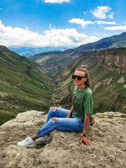 Naklejka na ściany i meble A girl on the background of the Khunzakh valley, Khunzakh waterfalls, Dagestan 2021
