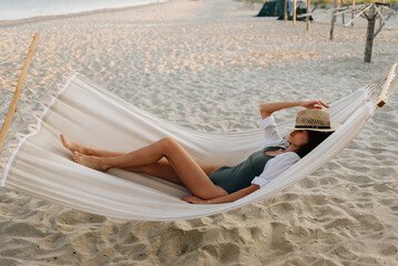 Vacation in Thailand. A young European woman rests in a hammock on an empty beach.