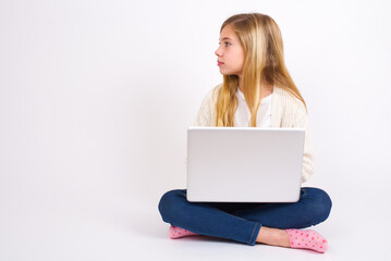 Fototapeta premium Side view of young happy smiling caucasian teen girl sitting with laptop in lotus position on white background 