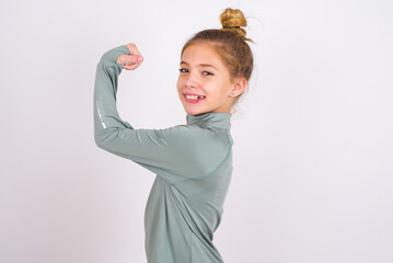 Portrait of powerful cheerful little caucasian kid girl with hair bun wearing technical shirt over...