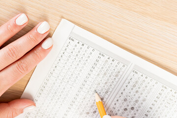 Obraz premium student hand testing in exercise and passing exam carbon paper computer sheet with pencil in school test room, education concept