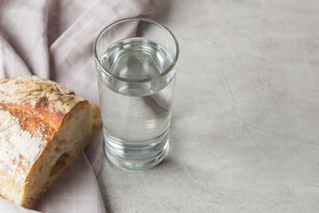 A glass of water on the kitchen table with a piece of bread on textiles. Natural food. Copy space.