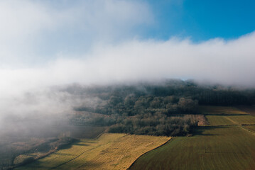 Un paysage de champs et un brouillard sur la montagne. La brume sur un paysage agricole. La campagne avec du brouillard sur des prés et une forêt.