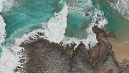 Crystal green waves crash against the stone coast of
