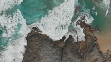 Crystal green waves crash against the stone coast of