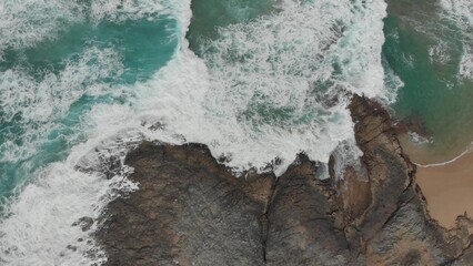 Crystal green waves crash against the stone coast of