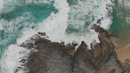 Crystal green waves crash against the stone coast of